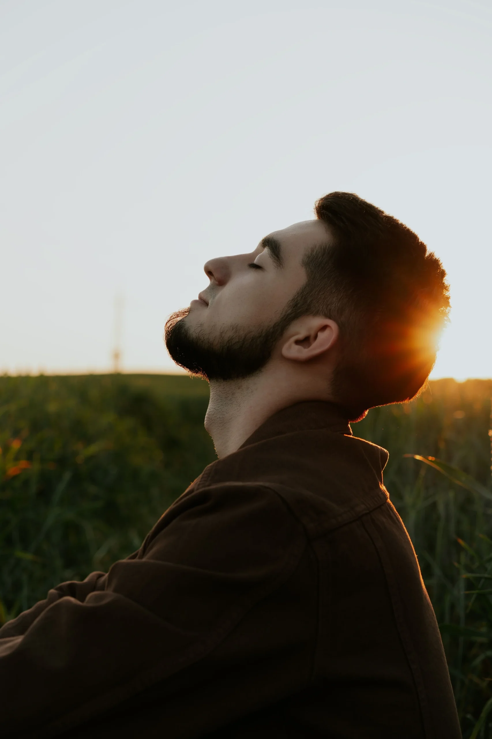 Hombre practicando respiración consciente al aire libre con los ojos cerrados