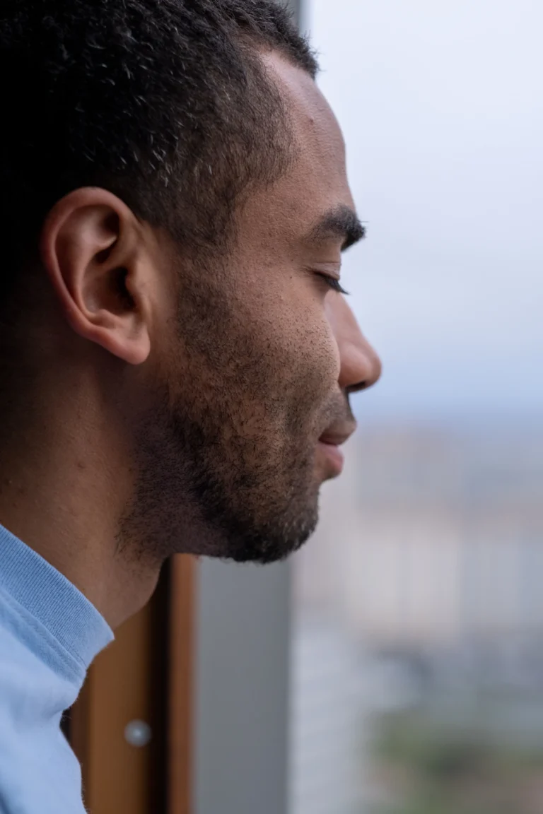 Hombre con los ojos cerrados junto a una ventana durante un momento de calma y atención consciente